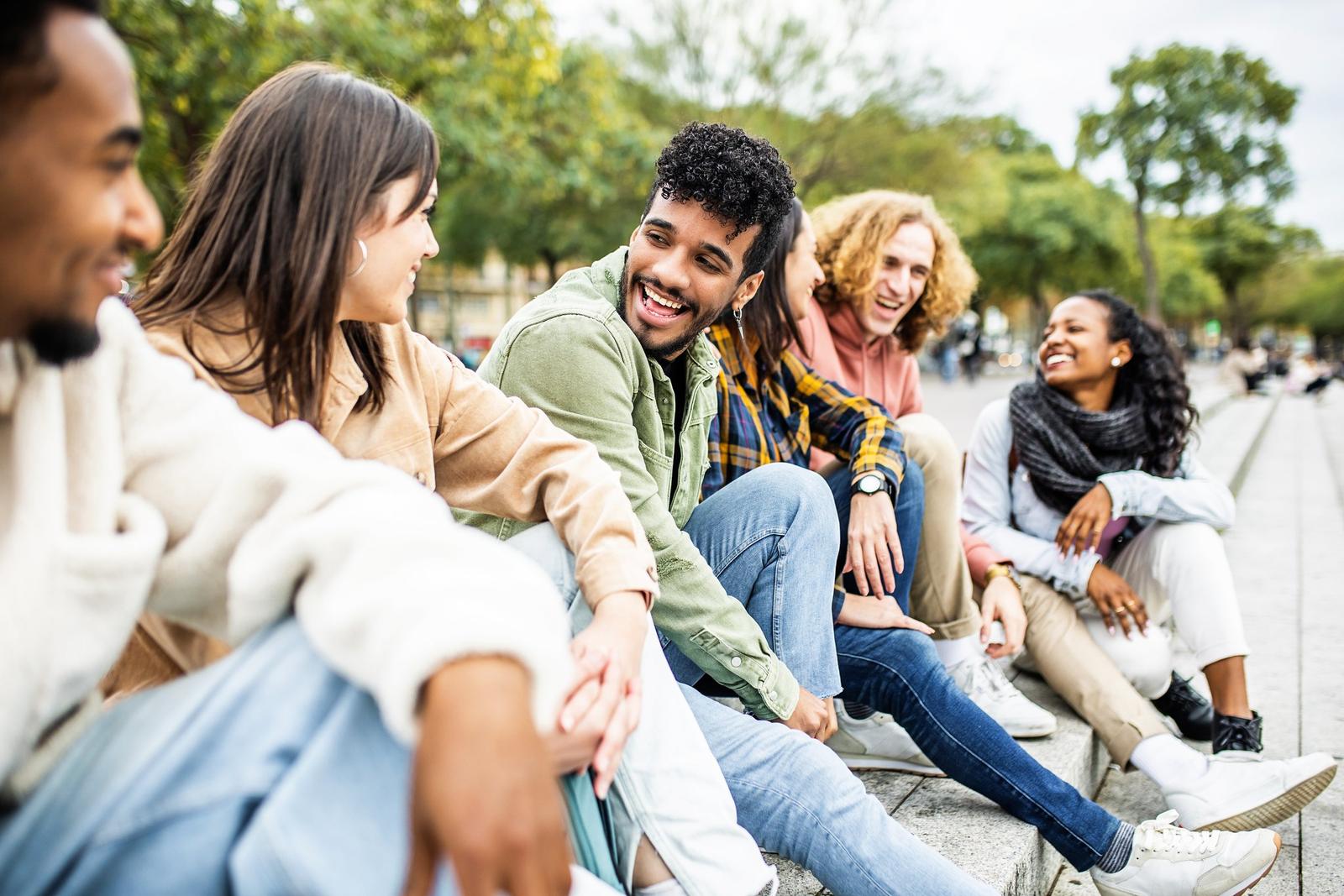 Friends sitting together outdoors, smiling and talking